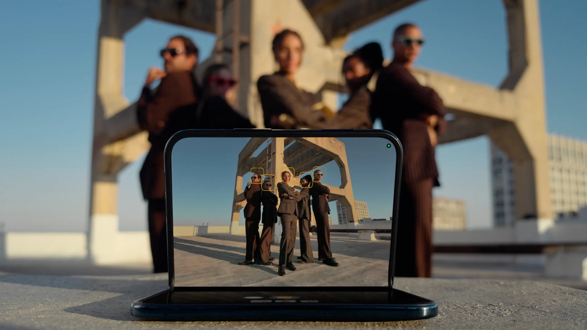 A partly folded iPhone Duo standing on a surface and photographing a group without a tripod