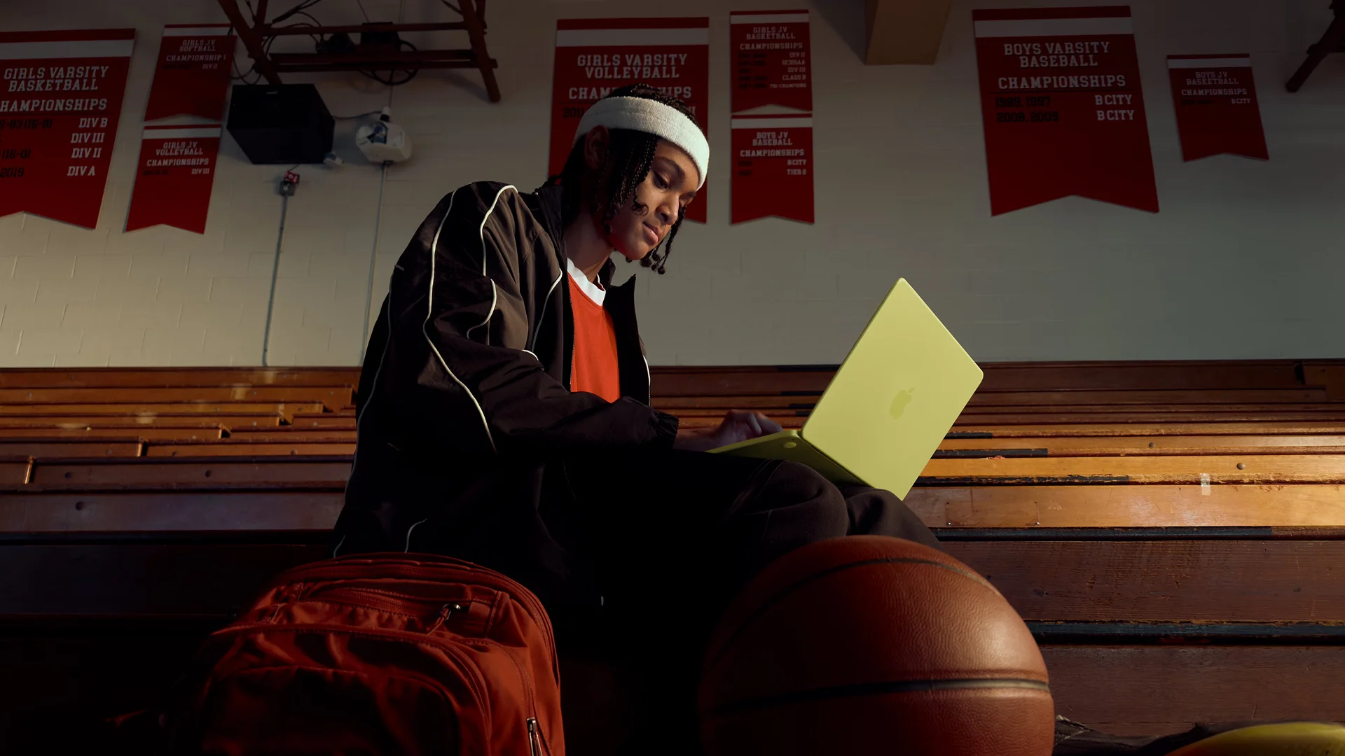 Student sitting on indoor bleachers and using a laptop away from the classroom